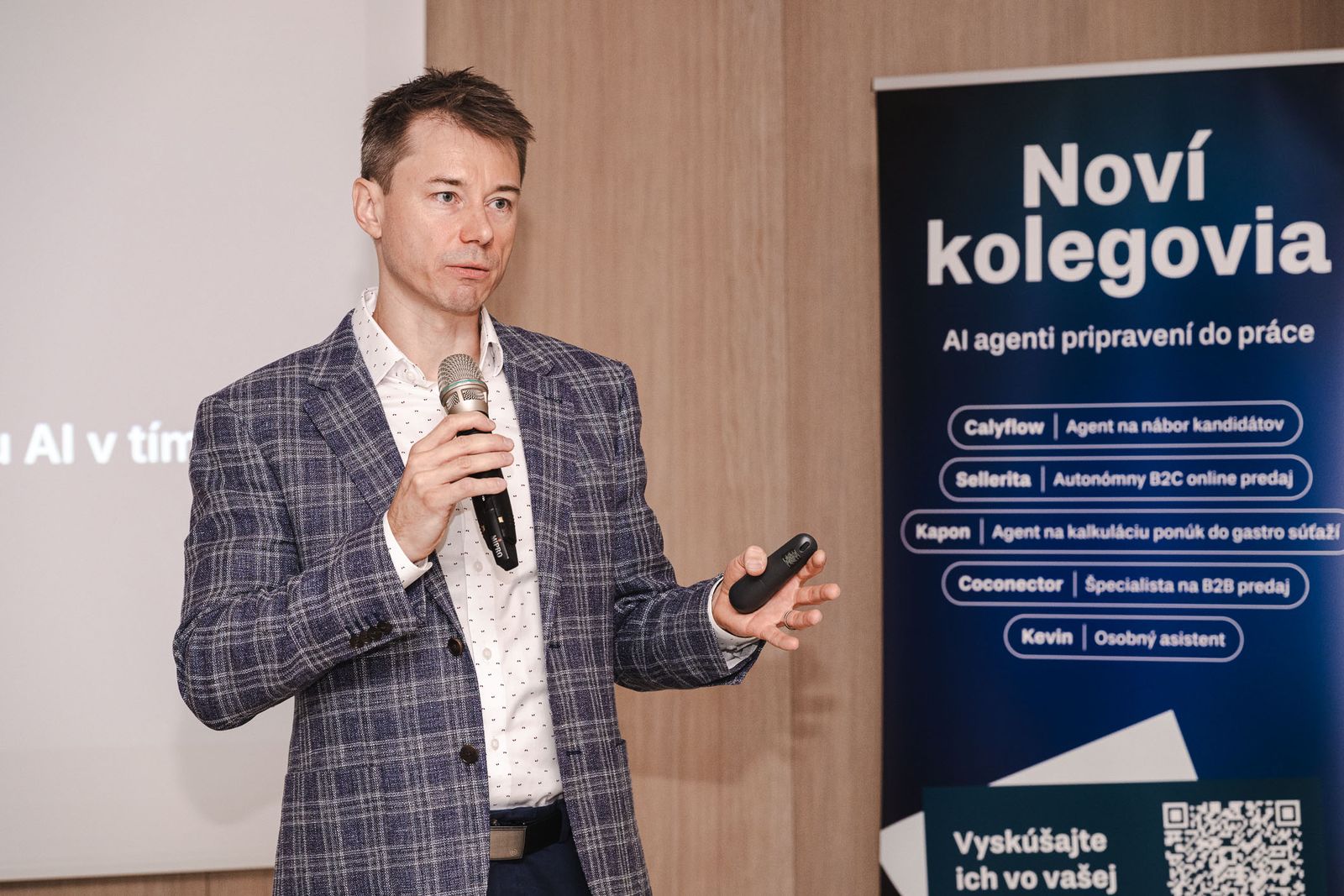 Michal Juhás beim Vortrag neben einem Roll-up mit KI-Agenten